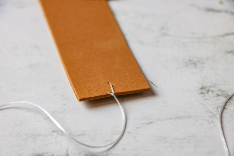 Closeup of brown foam strip with a hole in it and an elastic band tied to it
